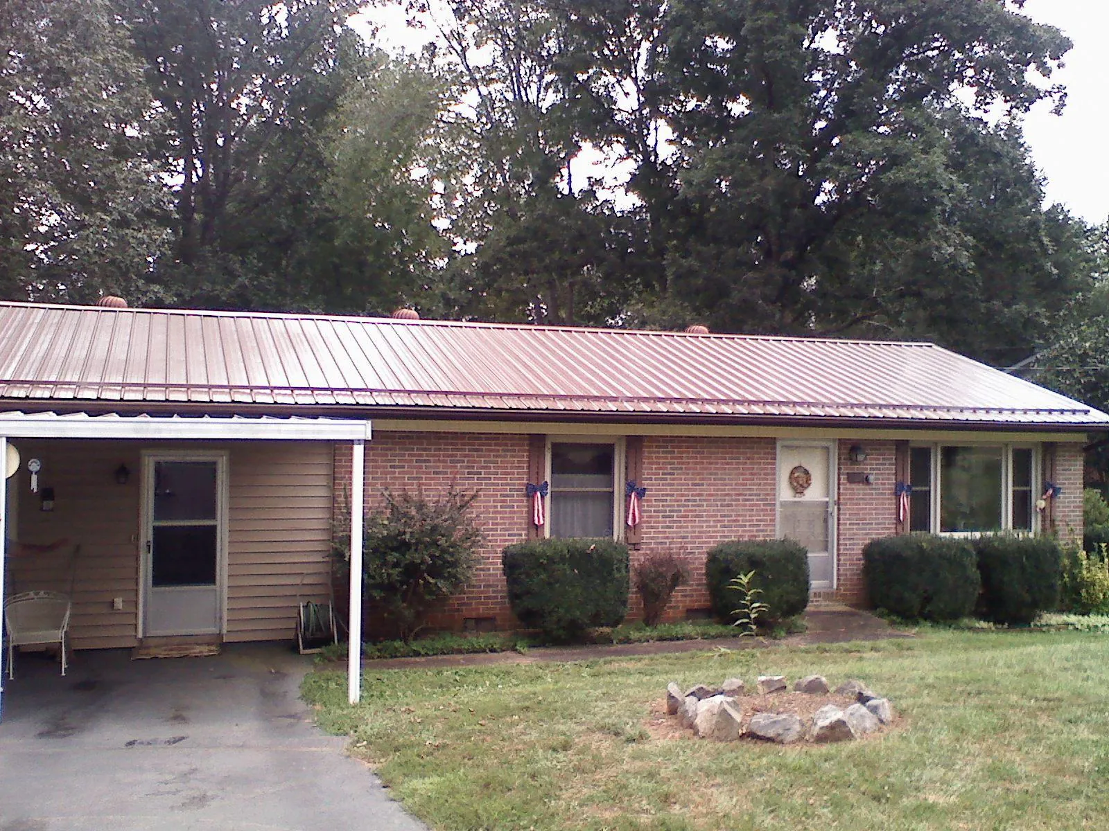 Bronze metal roof and carport on a brick ranch home — Roof Repair work by our crew in Spencerville